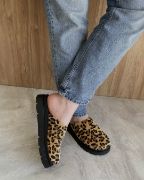 Πόδια από το γόνατο και κάτω μπροστινή όψη με τζιν παντελόνι και δίσολα clogs εξωφτερνα με κλειστή στρογγυλή μύτη σε λεοπαρ χρώμα από pony skin με το αριστερό πόδι σταυρωμένο μπρεοστά από το δεξί.