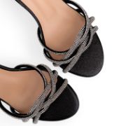 Γυναικεία πέδιλα σε μαύρο χρώμα από γκλίτερ με λουράκια από στρας στα δάκτυλα σε πλεκτο σχήμα κοντινό στα λουράκια σε λευκό φόντο.