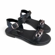 Ζευγάρι γυναικεία σανδάλια με μαύρη σόλα, μαύρη φάσα με ασημί αλυσίδα στα δάχτυλα και μύρη μπαρέτα στο κουντεπιέ πλάγια εξωτερική όψη σε λευκό φόντο.