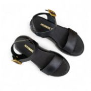 Γυναικεία δερμάτινα δίσολα σανδάλια flatforms με μαύρη σόλα, μαύρη μπαρετα με χρυσή αγκράφα και μαύρη φάσα στα δάχτυλα επάνω όψη σε λευκό φόντο.