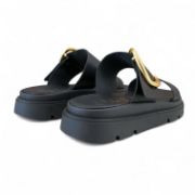 Γυναικείες παντόφλες δίσολες με διπλή φάσα και μεγάλο χρυσό μεταλλικό διακοσμητικό σε όλο μαύρο χρώμα πίσω όψη σε λευκό φόντο.