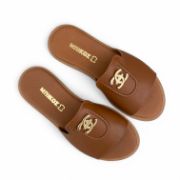 Γυναικείες φλατ παντόφλες με μπεζ σόλα και φαρδιά φάσα σε ταμπά χρώμα και μικρό χτυσό διακοσμητικό επάνω όψη σε λευκό φόντο.