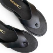 Γυναικείες φλατ δερμάτινες σαγιονάρες σε όλο μαύρο χρώμα επάνω όψη σε λευκό φόντο.