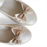 Παιδικές μπαλαρίνες σε ιβουάρ χρώμα.Κοντινό στο διακοσμητικό φιογκάκι με γκλίτερ και στρας σε λευκό φόντο.